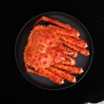 Top view of cooked Alaskan red king crab on black plate