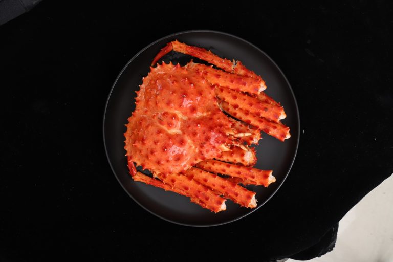 Top view of cooked Alaskan red king crab on black plate