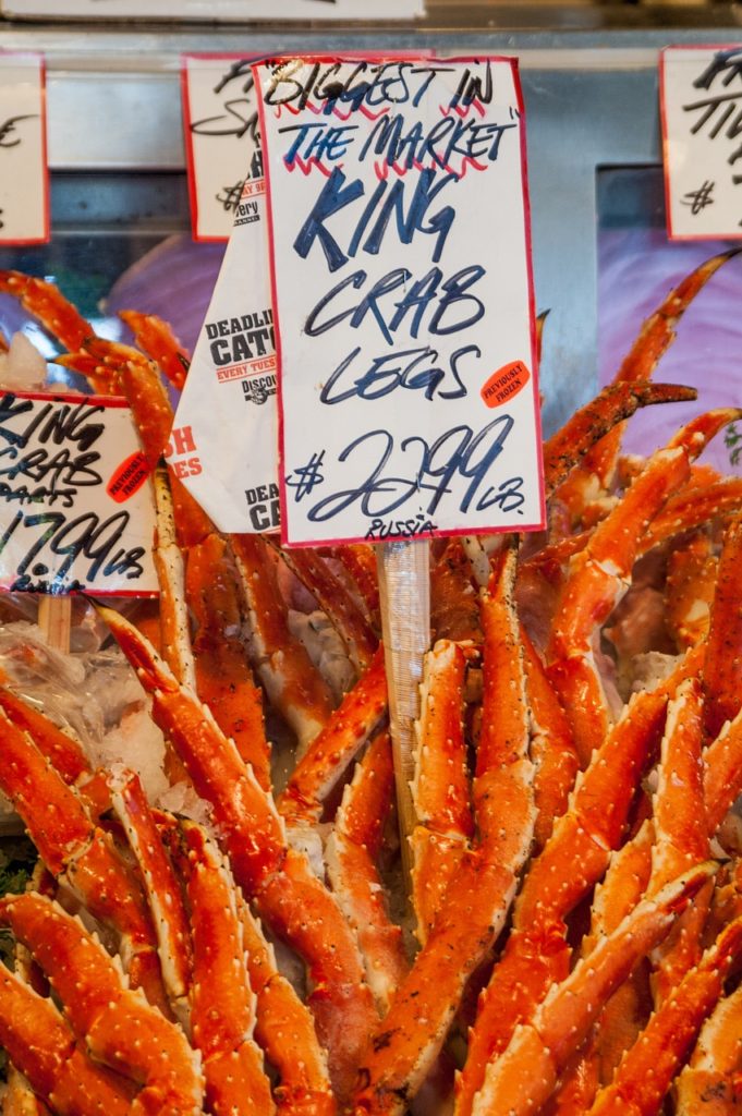 a bunch of alaskan red king crab legs in the market with price tag