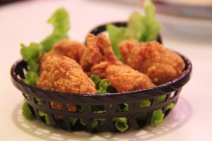 deep fried chicken drumpsticks with vegetables in black basket