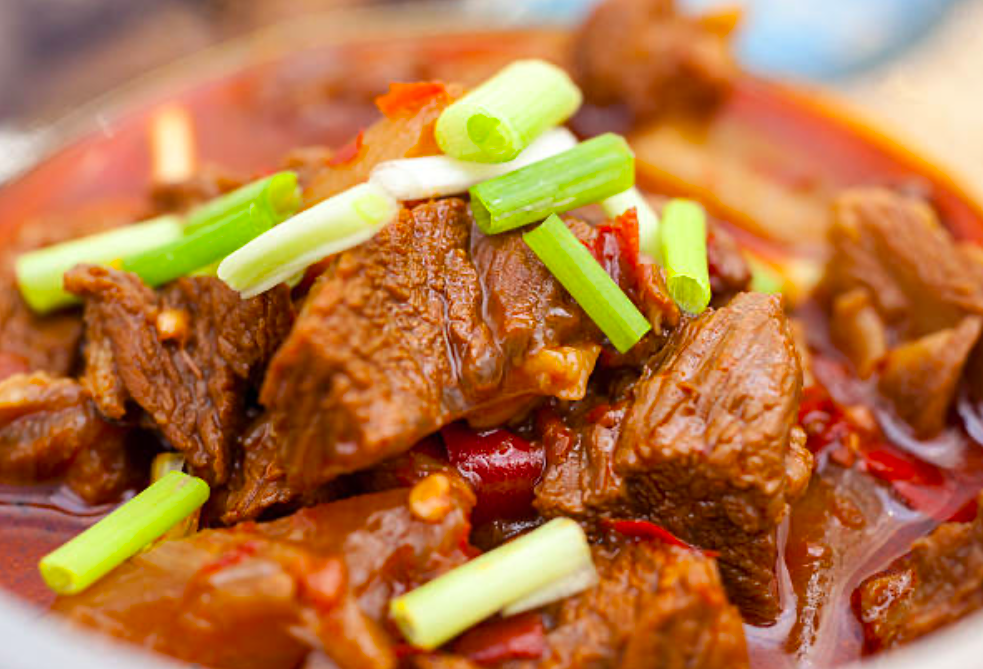 slow cooker beef stew topped with spring onions