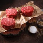 three filet mignon the most tender steak cuts on a paper nicely marbled with salt and pepper