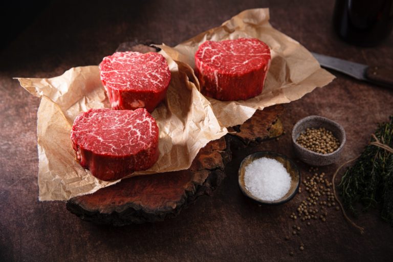 three filet mignon the most tender steak cuts on a paper nicely marbled with salt and pepper