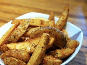 Baked potato wedge with salt and pepper in a white bowl