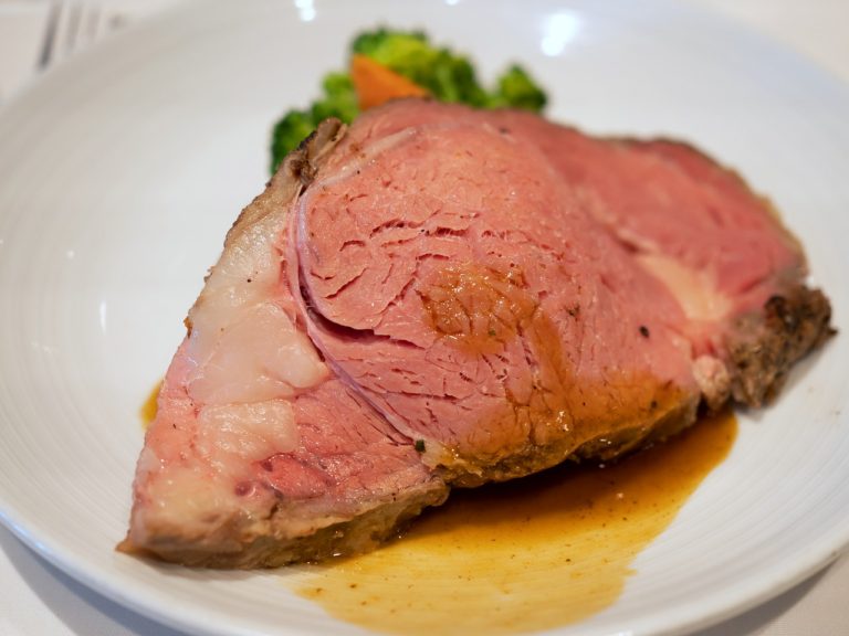 medium rare prime rib roast slice in a white dish