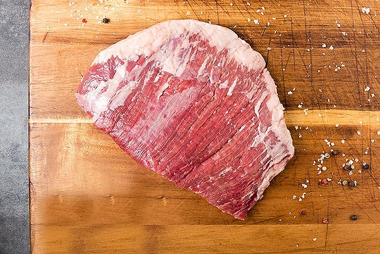 Grass fed Flank Steak on wooden chopping board leanest steak cuts