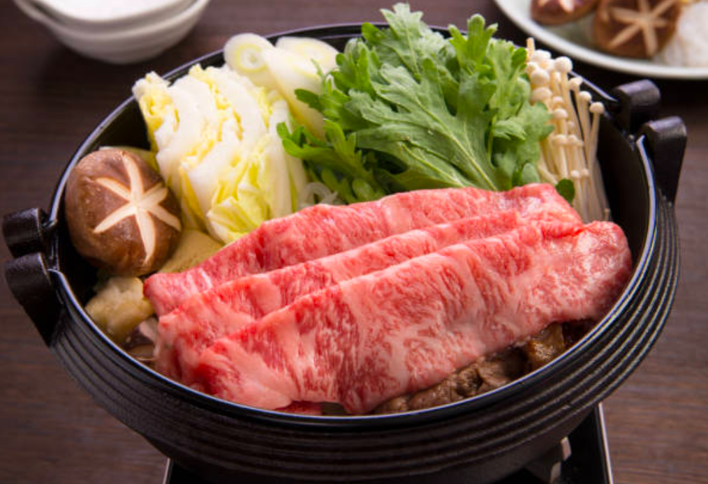 Sukiyaki Japanese hot pot wagyu beef slices with rich marbling and vegetables in a shallow iron pot