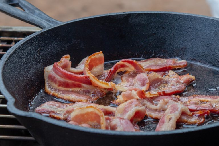 pan frying bacon on a cast iron pan