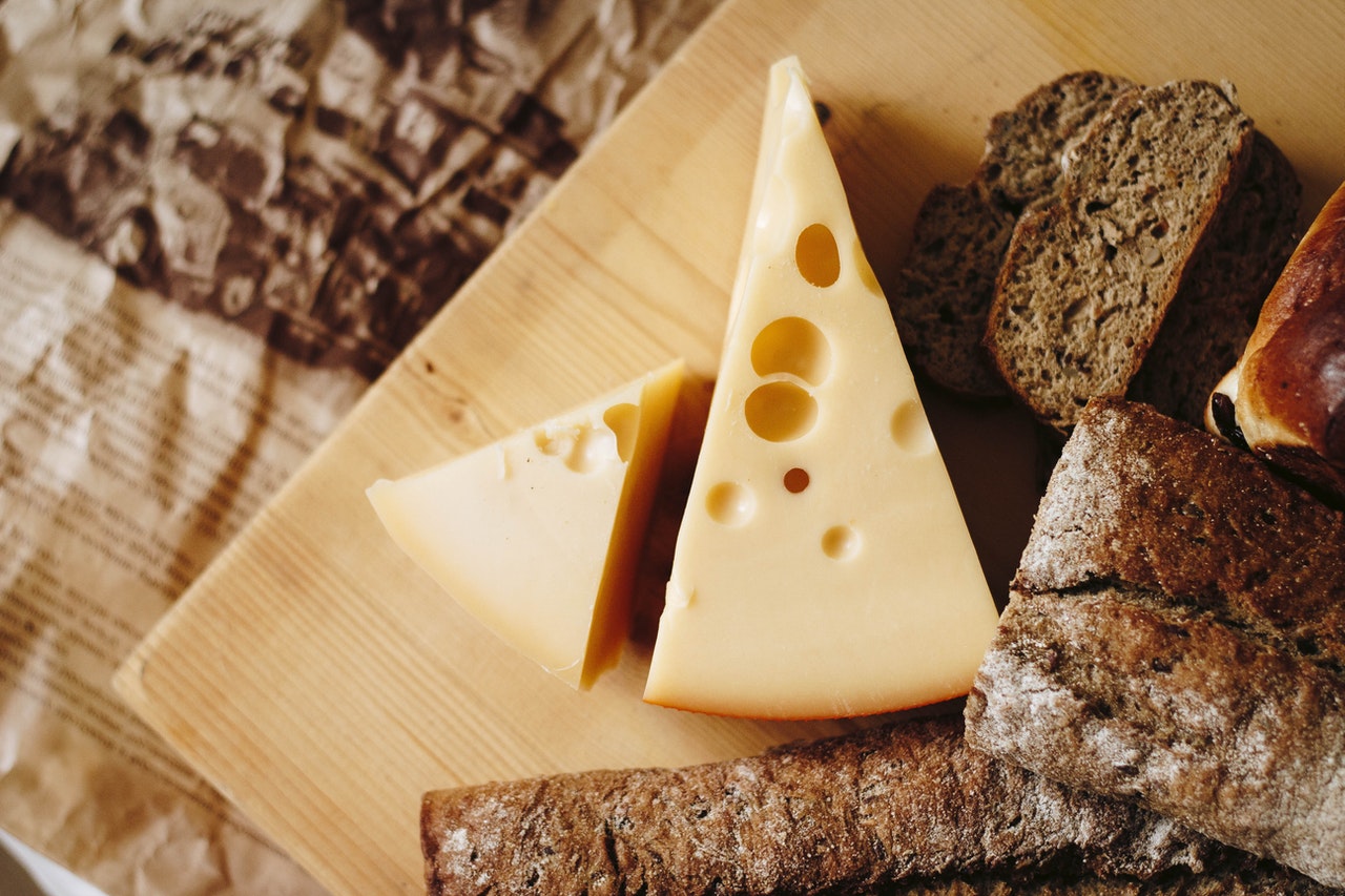 swiss cheese on a wooden board with bread