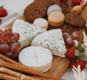 white mold brie and blue cheese with grapes grissini macaron on wooden board