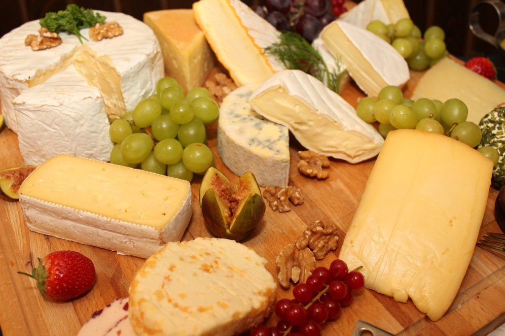 brie blue soft cheeses with fruits on wooden board