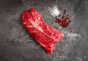 Uncooked Hanger Steak with salt and pepper on grey board