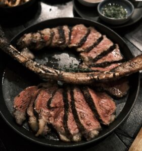 Reverse sear tomahawk steak and sliced with a large bone close up